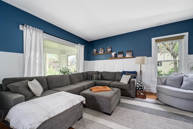 living room with a wainscoted wall, healthy amount of natural light, and wood finished floors