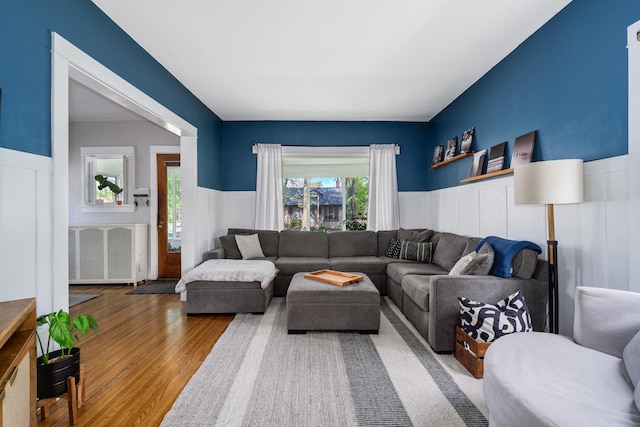 living area featuring wood finished floors, wainscoting, a decorative wall, and radiator heating unit