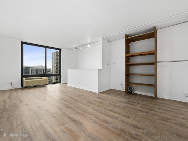 1221 N Dearborn St Unit 1401S, Chicago, IL 60610 - unfurnished living room with rail lighting, wood finished floors, baseboards, expansive windows, and a wall unit AC