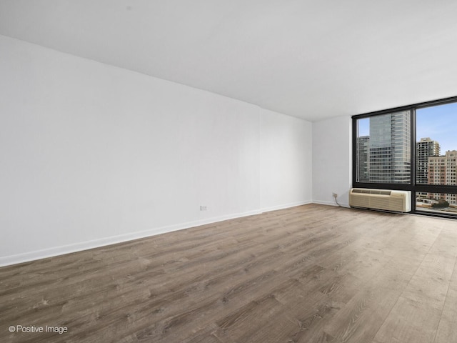 1221 N Dearborn St Unit 1401S, Chicago, IL 60610 - spare room with wood finished floors, baseboards, a wall of windows, a city view, and a wall mounted air conditioner