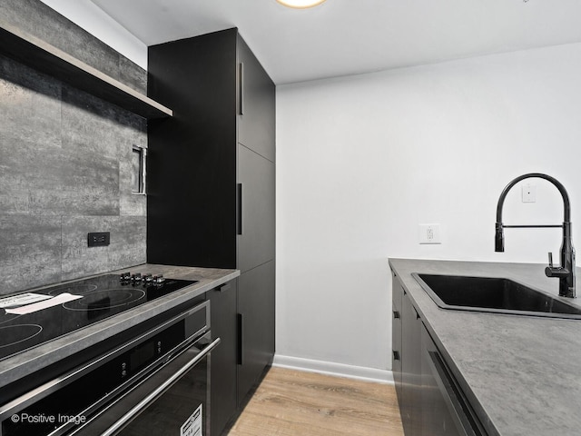 1221 N Dearborn St Unit 1401S, Chicago, IL 60610 - kitchen featuring a sink, black appliances, light wood-type flooring, dark cabinetry, and decorative backsplash