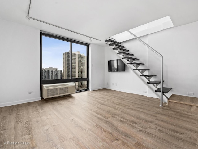 1221 N Dearborn St Unit 1401S, Chicago, IL 60610 - unfurnished living room with wood finished floors, stairway, a wall mounted air conditioner, track lighting, and baseboards