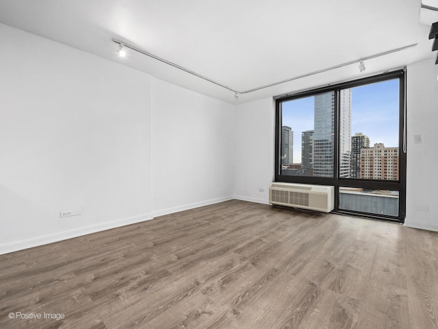 1221 N Dearborn St Unit 1401S, Chicago, IL 60610 - spare room with track lighting, wood finished floors, baseboards, a view of city, and a wall mounted air conditioner
