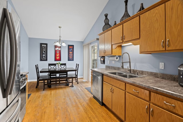 kitchen with stainless steel appliances, a sink, light wood-style flooring, a chandelier, and high vaulted ceiling