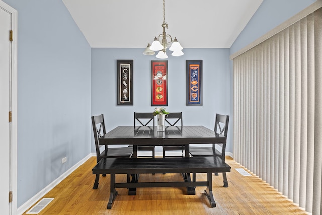 dining room with a chandelier, light wood-style flooring, baseboards, and vaulted ceiling