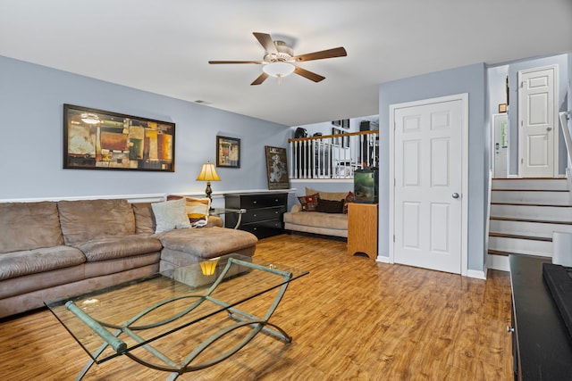 living room featuring a ceiling fan, stairway, and wood finished floors