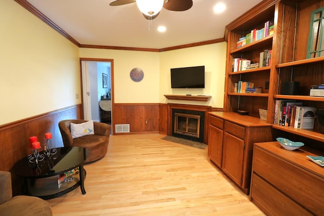 2210 Sandburg Dr, Aurora, IL 60506 - living room featuring wainscoting, a fireplace with flush hearth, crown molding, light wood-type flooring, and a ceiling fan