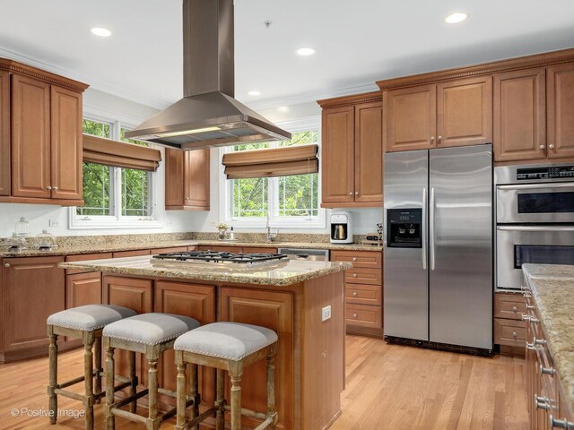 220 Kings Ct, La Grange Park, IL 60526 - kitchen featuring appliances with stainless steel finishes, island exhaust hood, a center island, a breakfast bar area, and light wood-style flooring