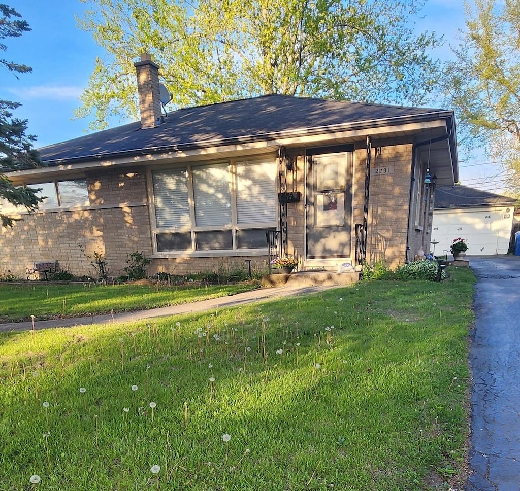 view of front of house featuring a front lawn, a chimney, and brick siding