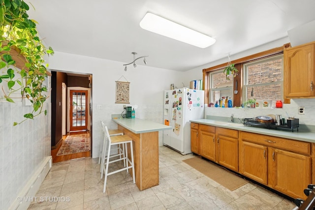 4842 N California Ave, Chicago, IL 60625 - kitchen with white fridge with ice dispenser, light countertops, a breakfast bar area, a sink, and tile walls