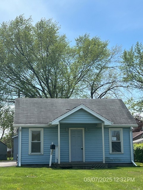 bungalow-style house with a front yard and a shingled roof
