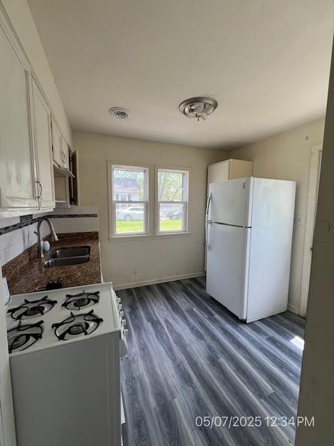 kitchen featuring freestanding refrigerator, a sink, gas range, dark wood finished floors, and white cabinets