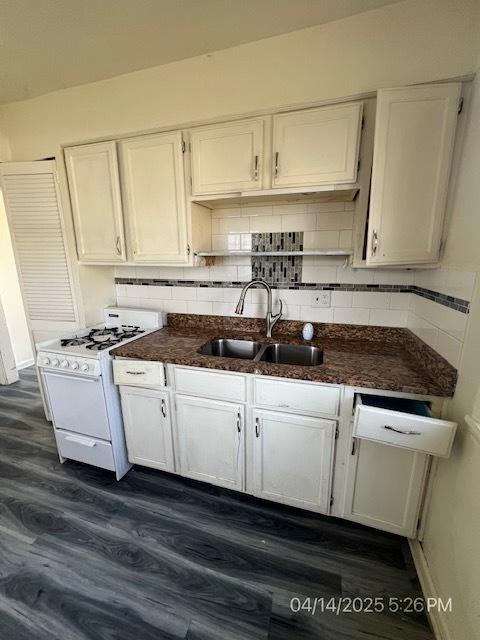 kitchen featuring a sink, white gas range oven, and white cabinets