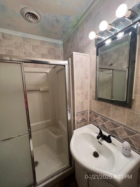 full bathroom featuring tile walls, a shower stall, and a sink