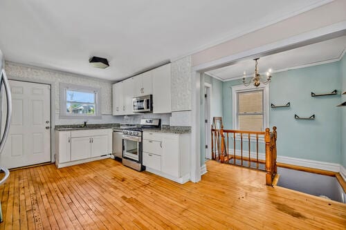 1144 N Austin Blvd, Oak Park, IL 60302 - kitchen featuring stainless steel appliances, white cabinets, light wood-type flooring, a chandelier, and ornamental molding