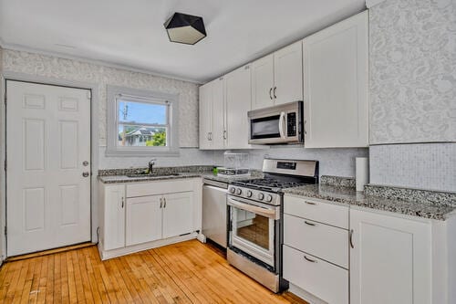 1144 N Austin Blvd, Oak Park, IL 60302 - kitchen featuring stainless steel appliances, a sink, white cabinets, and stone counters