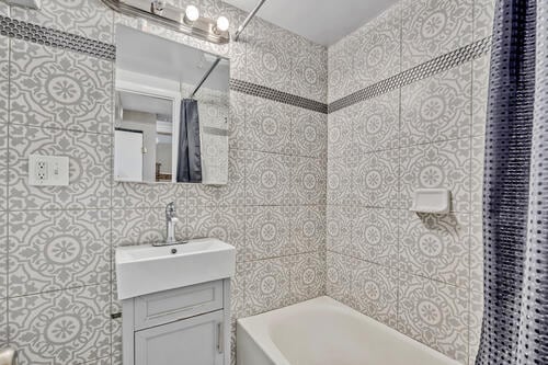 1144 N Austin Blvd, Oak Park, IL 60302 - bathroom featuring vanity, tile walls, and shower / bathtub combination with curtain