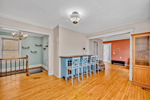 1144 N Austin Blvd, Oak Park, IL 60302 - empty room featuring a chandelier, wood-type flooring, baseboards, and crown molding