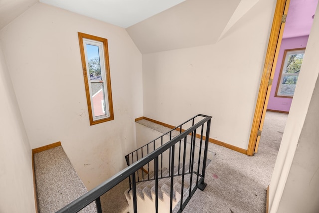 stairs with carpet flooring, vaulted ceiling, and baseboards