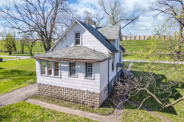 view of home's exterior featuring a shingled roof, a yard, and a chimney