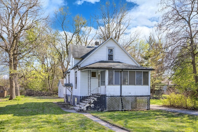 view of front facade with a shingled roof, a front yard, and a chimney
