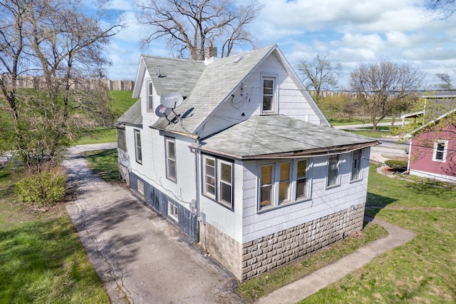view of side of home featuring roof with shingles, a chimney, and a yard