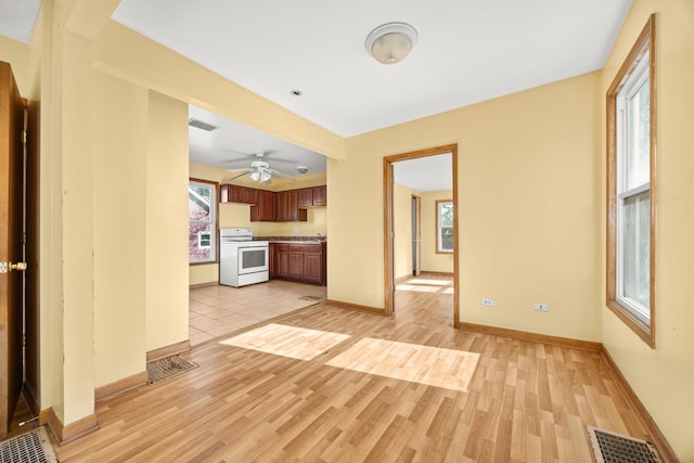 unfurnished living room with healthy amount of natural light, light wood-style flooring, baseboards, and ceiling fan