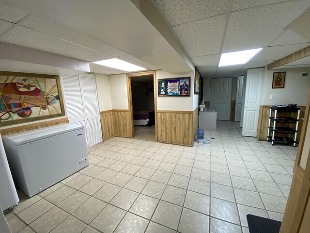 3846 Brummel St, Skokie, IL 60076 - finished basement with a paneled ceiling, wainscoting, refrigerator, light tile patterned flooring, and wooden walls