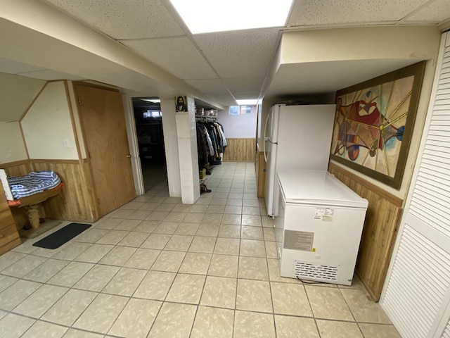 3846 Brummel St, Skokie, IL 60076 - finished below grade area with a wainscoted wall, a paneled ceiling, wooden walls, fridge, and light tile patterned floors