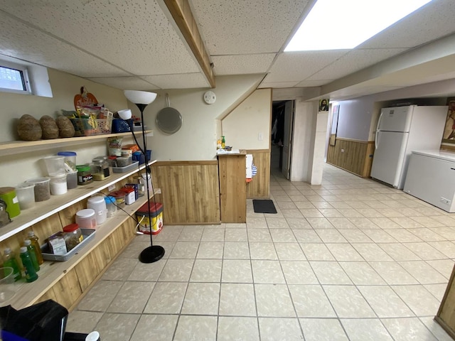 3846 Brummel St, Skokie, IL 60076 - basement featuring a wainscoted wall, a paneled ceiling, freestanding refrigerator, fridge, and wooden walls