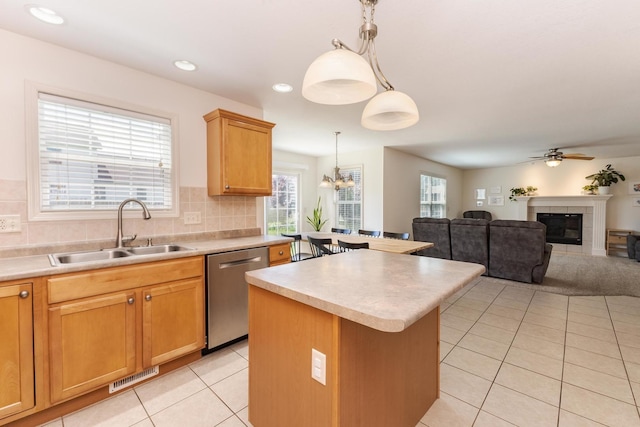 kitchen featuring a sink, dishwasher, a kitchen island, light tile patterned floors, and light countertops