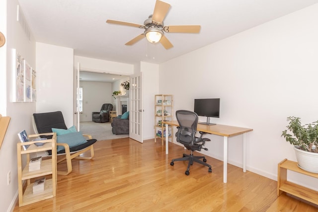 office space with light wood finished floors, ceiling fan, french doors, and baseboards