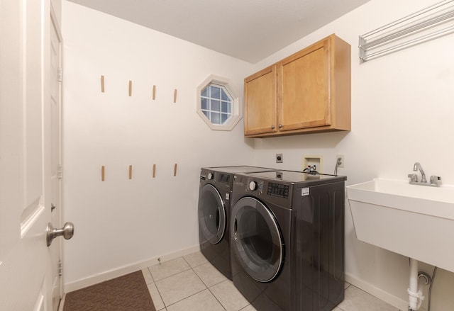 washroom with cabinet space, washing machine and dryer, light tile patterned flooring, and baseboards