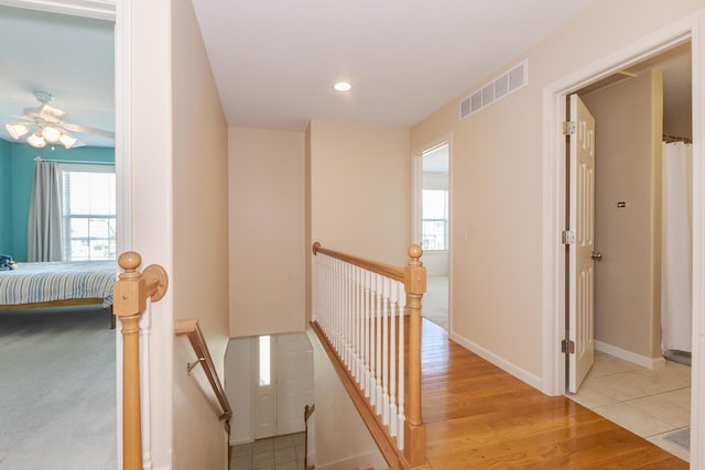 corridor with an upstairs landing, baseboards, recessed lighting, and light wood finished floors