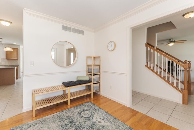 living area featuring a ceiling fan, crown molding, wood finished floors, stairs, and baseboards