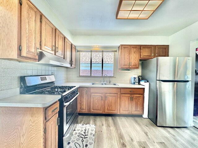 8344 N Milwaukee Ave, Niles, IL 60714 - kitchen featuring stainless steel appliances, under cabinet range hood, a sink, light wood-style flooring, and light countertops