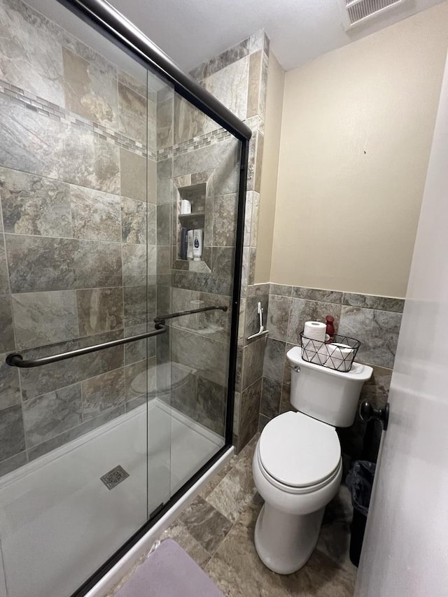 7427 Mccurry Rd, Roscoe, IL 61073 - full bathroom featuring toilet, a shower stall, a wainscoted wall, and tile walls