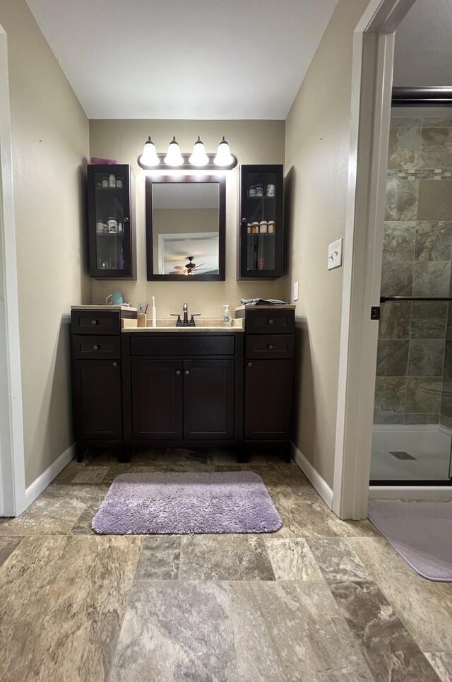 7427 Mccurry Rd, Roscoe, IL 61073 - bathroom with baseboards, tiled shower, vanity, and stone finish flooring