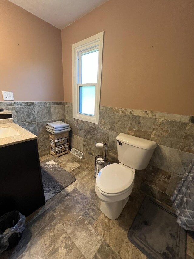 7427 Mccurry Rd, Roscoe, IL 61073 - bathroom featuring tile walls, toilet, wainscoting, and vanity
