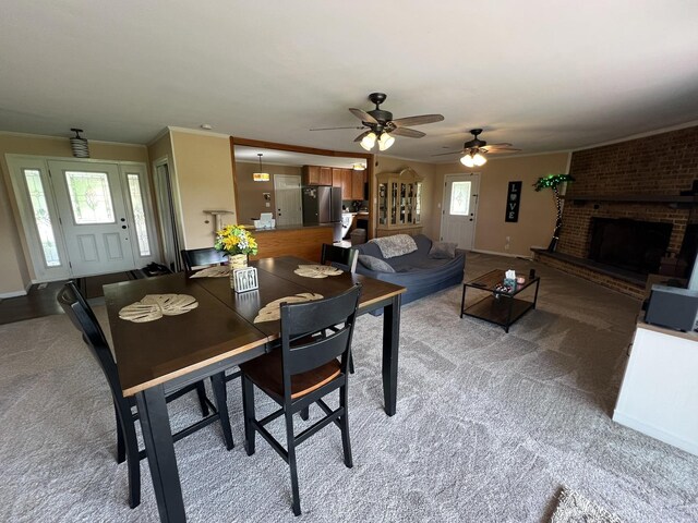 7427 Mccurry Rd, Roscoe, IL 61073 - dining space with light colored carpet, a fireplace, crown molding, ceiling fan, and baseboards