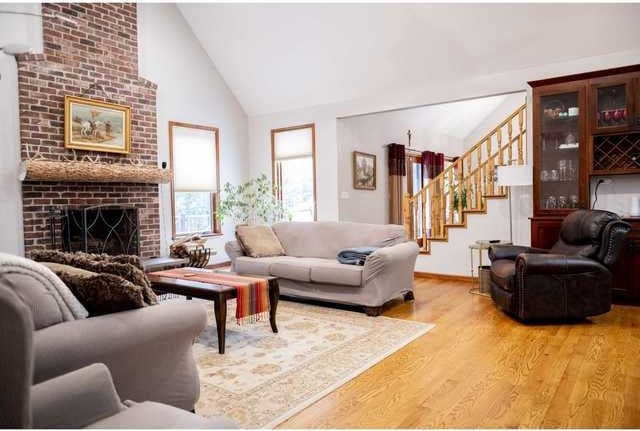 24-114 Lake Carroll Blvd, Lake Carroll, IL 61046 - living area featuring light wood-type flooring, stairs, high vaulted ceiling, and a brick fireplace