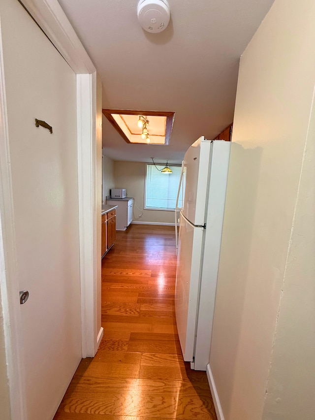 hall featuring light wood finished floors and baseboards