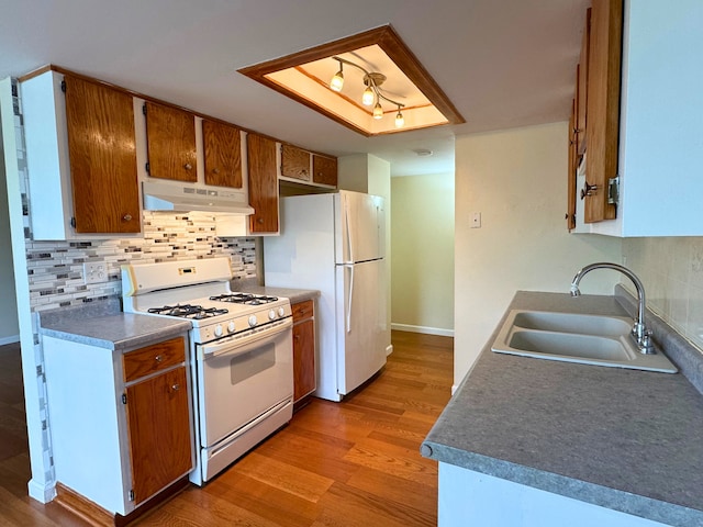 kitchen featuring white appliances, under cabinet range hood, a sink, and light wood-style flooring