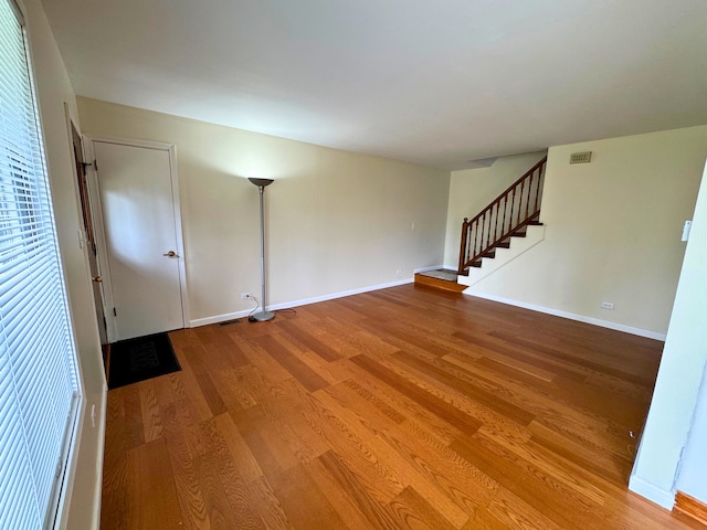 spare room featuring stairway, wood finished floors, and baseboards