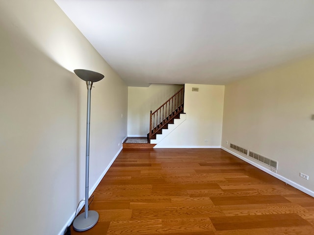 empty room with stairway, wood finished floors, and baseboards