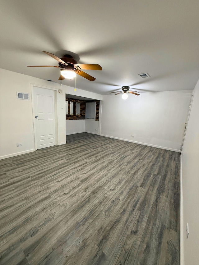 unfurnished living room with dark wood-style floors, a ceiling fan, and baseboards