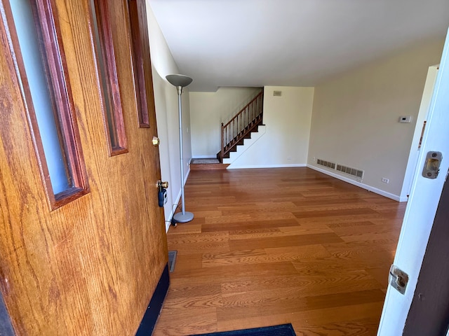 foyer with stairway, wood finished floors, and baseboards