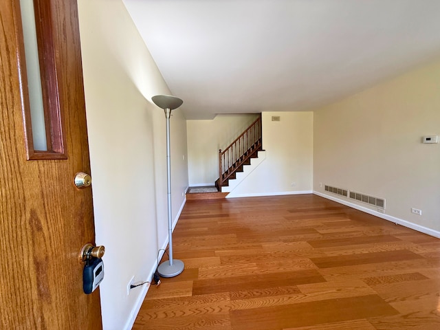 spare room with stairs, wood finished floors, and baseboards