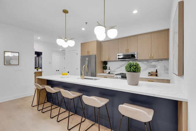 3204 N Kostner Ave Unit 307, Chicago, IL 60618 - kitchen featuring appliances with stainless steel finishes, a sink, a kitchen bar, light stone counters, and recessed lighting