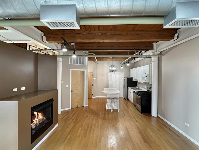below grade area with freestanding refrigerator, light wood-style flooring, baseboards, and a warm lit fireplace